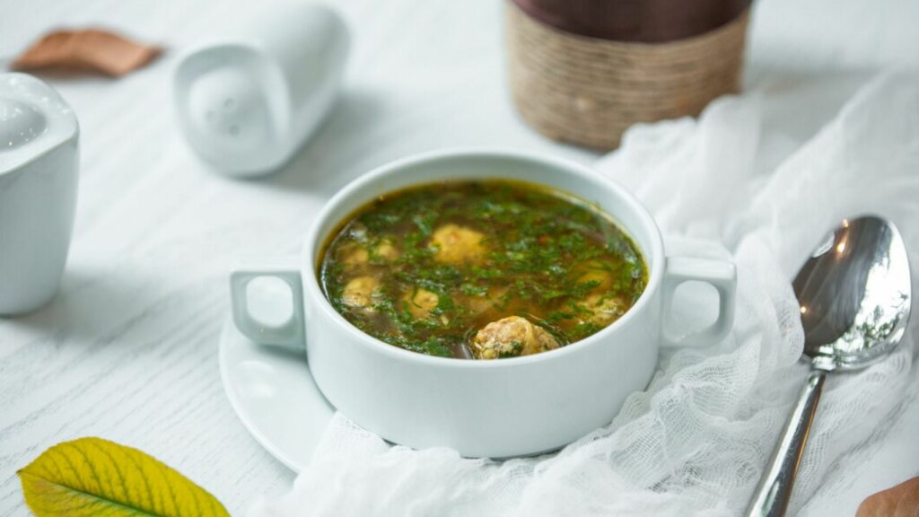 A picture of green soup with meat balls